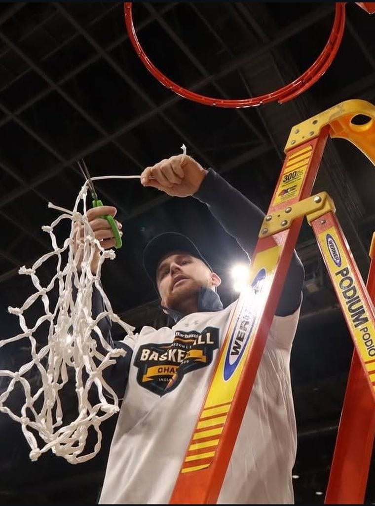 Coach Blake Kingsley cutting down the net after Robert Morris won the 2025 Horizon League championship