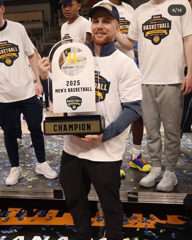Coach Blake Kingsley holding the 2025 Horizon League men's basketball championship trophy